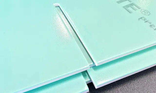 Mehrere hellgrüne Hartschaumplatten liegen übereinander. Eine Platte zeigt eine gerade Schnittkante, die das Schneiden von Hartschaumplatten verdeutlicht.