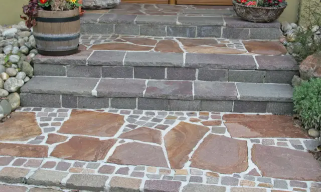 Stufen mit polygonalplatten verlegen. Große, unregelmäßige Steinplatten und kleine Pflastersteine bilden ein schönes Muster.