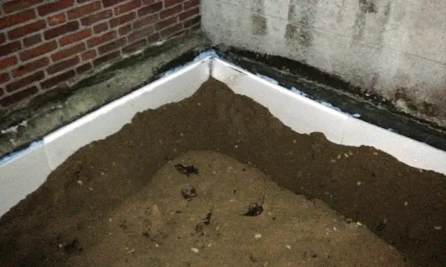 Styrodurplatten werden auf Bitumen geklebt, um eine Dämmung zu schaffen. Sand liegt auf den Platten.