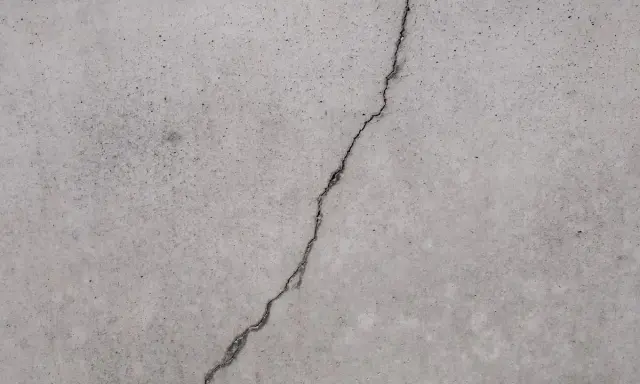 Ein Riss im Betonboden zeigt die Notwendigkeit, den Estrich reparieren zu lassen, um weitere Schäden zu vermeiden.