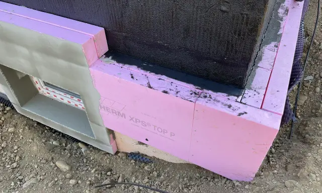 Dämmung wird angebracht. Pinke Styrodurplatten werden sorgfältig an die Wand geklebt, um das Gebäude zu isolieren.