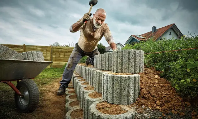 Mann setzt mit Gummihammer Pflanzsteine für eine neue Gartenmauer.