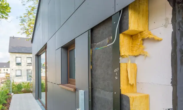 Fassade im Bau: WDVS selber machen mit gelber Steinwolle-Dämmung, die an einer grauen Verkleidung angebracht wird.