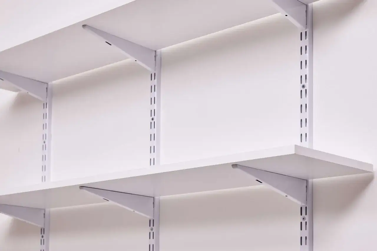 Wei&szlig;e Regale mit Metalltr&auml;gern an einer Wand. So kann man ein Regal anbringen, flexibel und stabil.