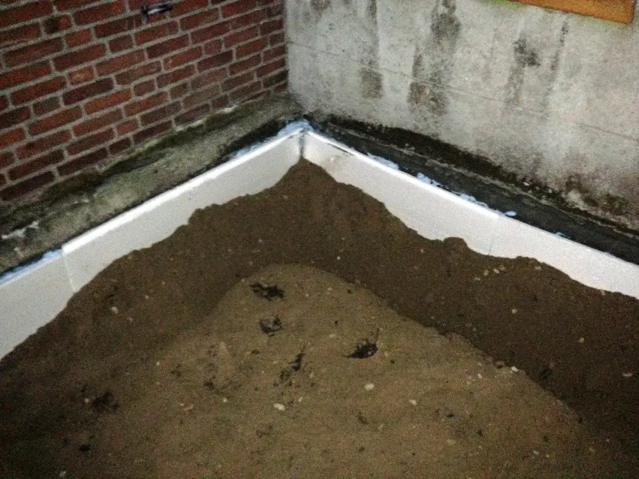 Styrodurplatten werden auf Bitumen geklebt, um eine Dämmung zu schaffen. Sand füllt den Bereich.