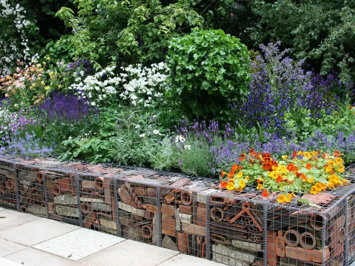 Kreative Ideen Gartenmauer: Gabionen gef&uuml;llt mit Ziegeln und Rohren, bepflanzt mit bunten Blumen und Lavendel.