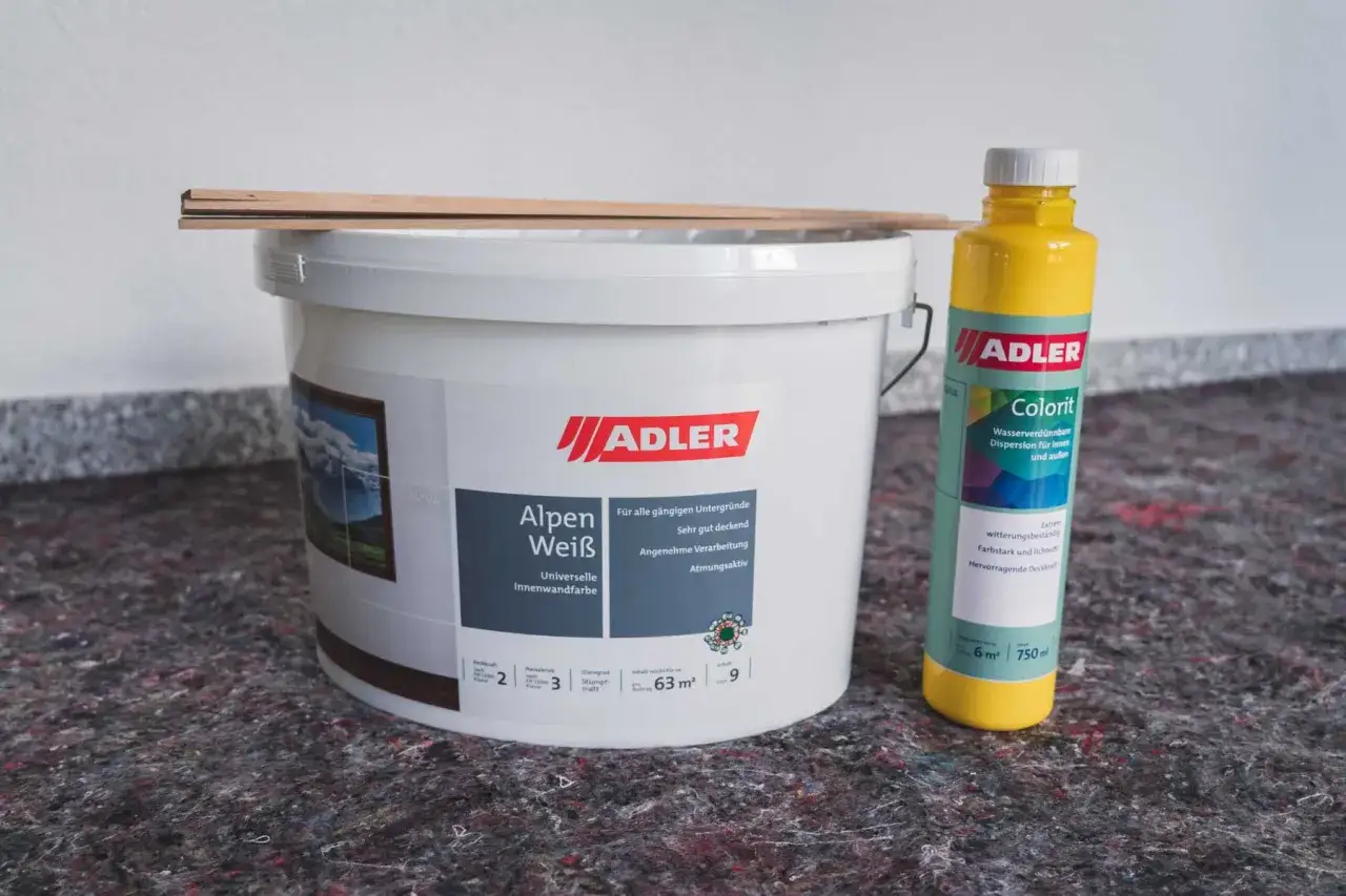 Eimer Alpen Wei&szlig; Wandfarbe, Flasche gelber Colorit zum Wandfarbe mischen, Holzleisten und Schutzvlies bereit f&uuml;r das Projekt.