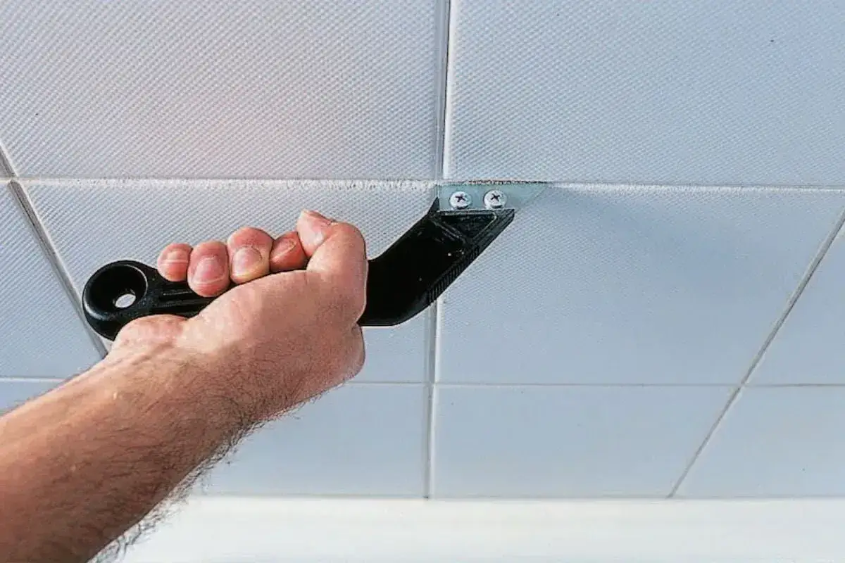 Hand uses a tool to scrape old grout from tile joints, preparing them for fugen ausbessern.