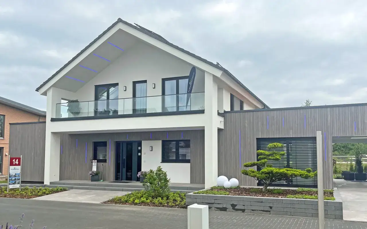 Modernes Haus mit Glasbalkon und blauer Beleuchtung. Hier finden Sie positive Schwabenhaus Erfahrungen, die das Design widerspiegeln.