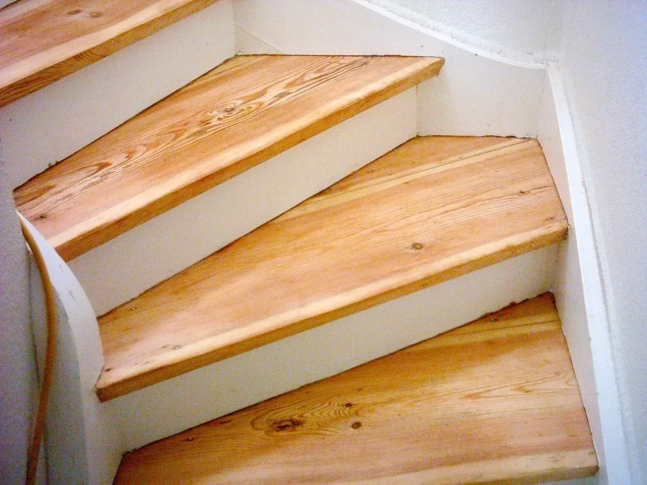 Holztreppe nach dem Boden schleifen mit hellem, natürlichem Holz und weißen Wangen.