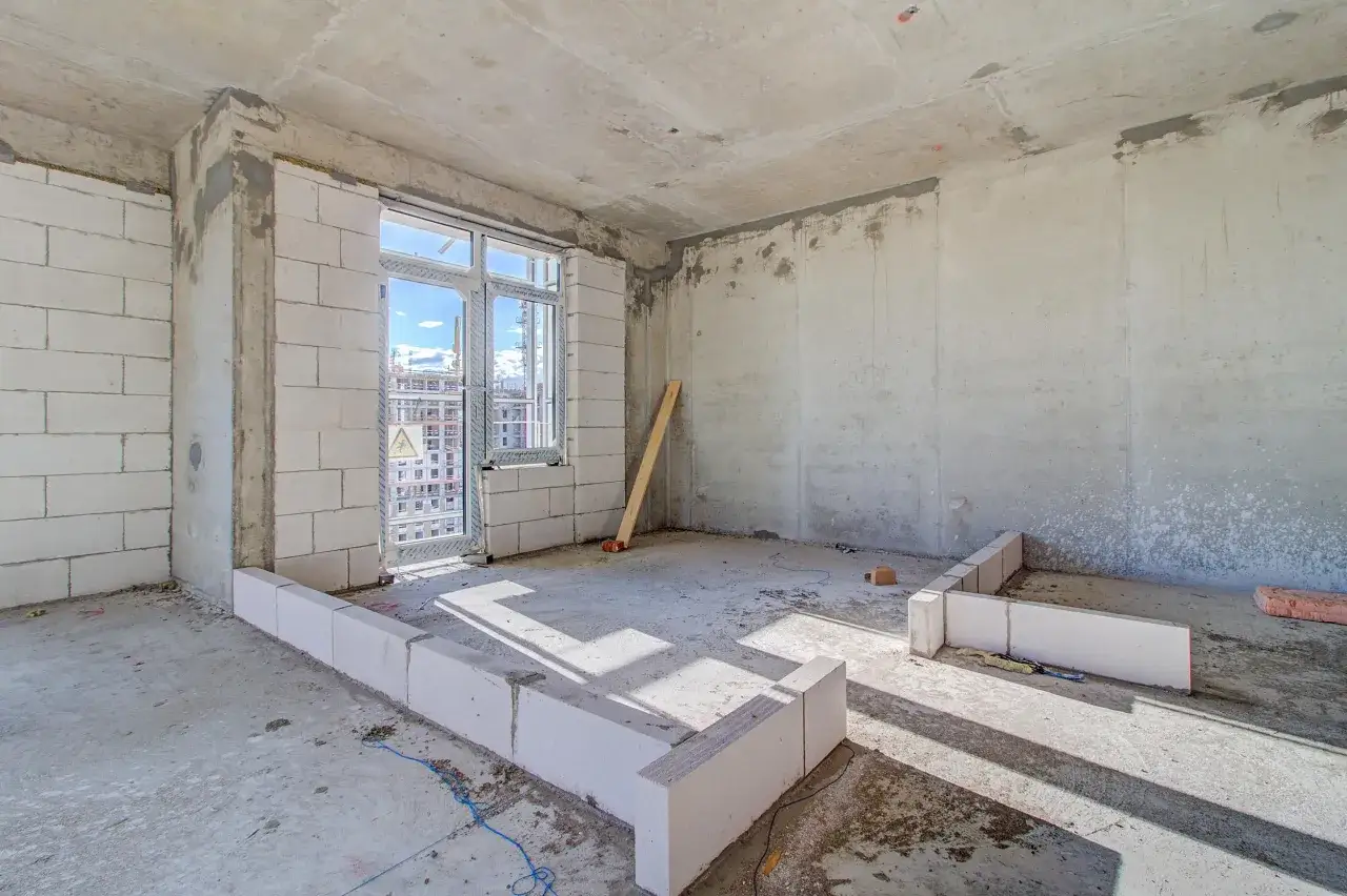 Einblick in den Rohbau: wei&szlig;e Ziegelsteine bilden die W&auml;nde, ein Fenster ist eingesetzt. So baut man ein Haus, Schritt f&uuml;r Schritt.