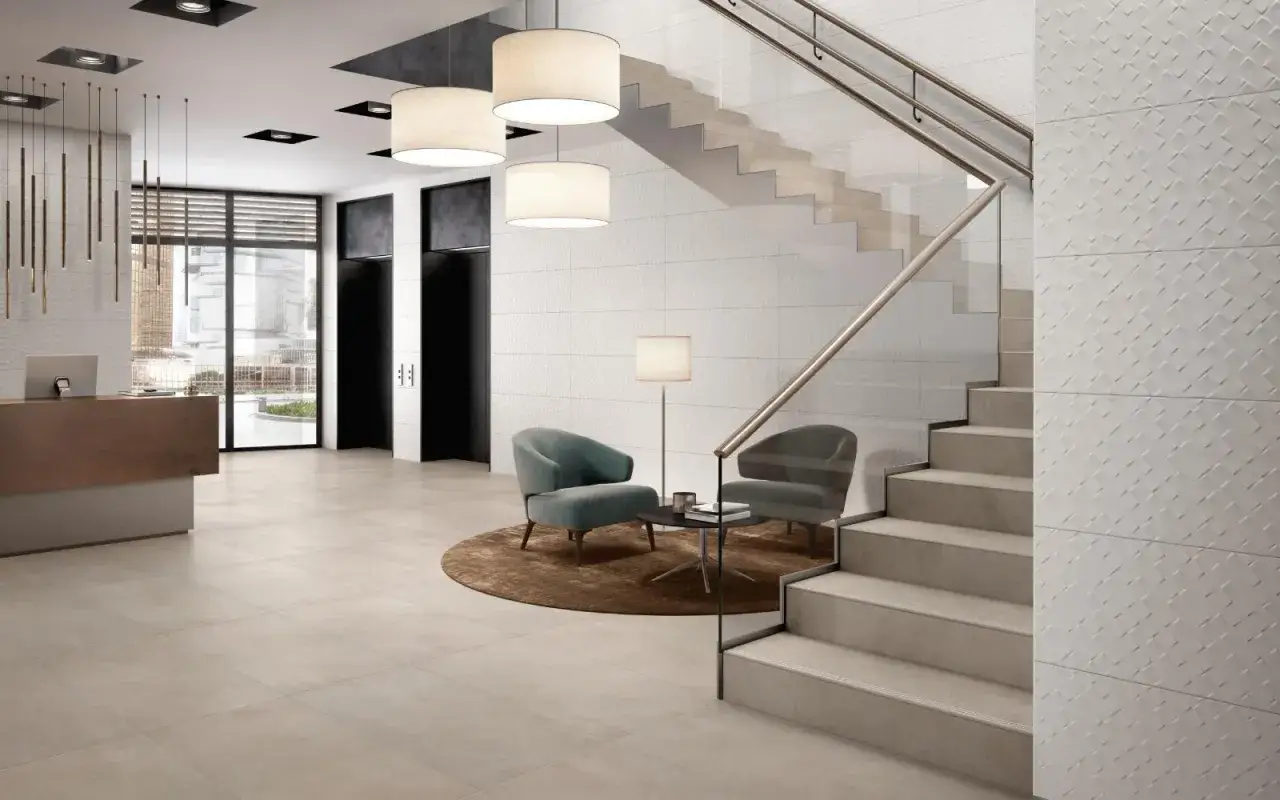 Moderne Lobby mit Empfangstresen, Sitzgelegenheiten und Treppe. Die Wandfliesen sind ein Blickfang und zeigen, wie man Fliesen sanieren kann, um ein stilvolles Ambiente zu schaffen.