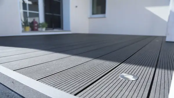 Moderne Terrasse mit grauen WPC Terrassendielen verlegen. Ein kleiner Bodenspot ist bereits integriert.