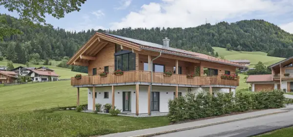 Ein modernes Holzhaus mit Balkonen und Blick auf grüne Hügel. So könnte man beschreiben, was ein Chalet in den Bergen ist.