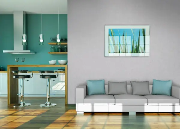 Modernes Wohnzimmer mit Vliestapete tapezieren. Ein weißes Sofa mit blauen und grauen Kissen steht vor einer Wand mit einem Bild von Gräsern. Daneben eine Küche mit Bar.