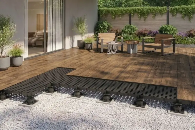 Terrassenplatten mit schwarzem Unterbau auf Kiesbett, bereit für die Montage. Ein moderner Aufbau für eine langlebige Terrasse.